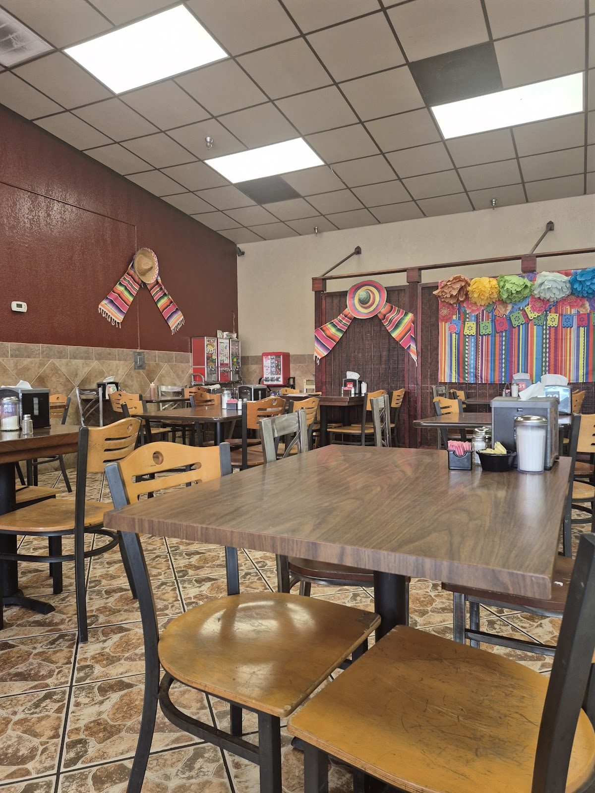 Dining room with wooden tables, papel picado and Mexican flag banners