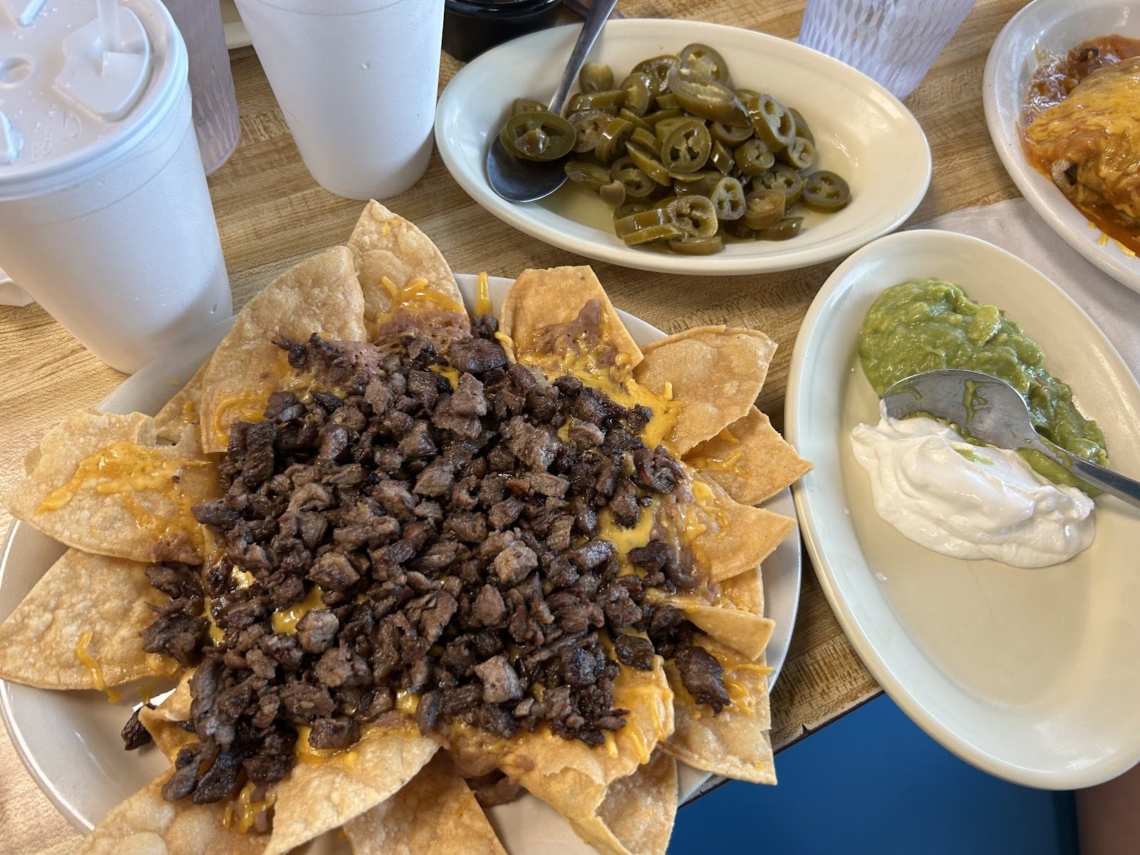 Nachos topped with beef fajita, with guacamole, sour cream and jalapeños